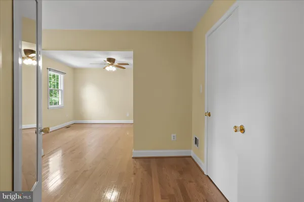 an empty room with wooden floor and a ceiling fan