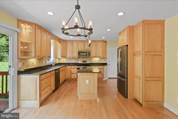 a kitchen with kitchen island granite countertop a sink cabinets and stainless steel appliances