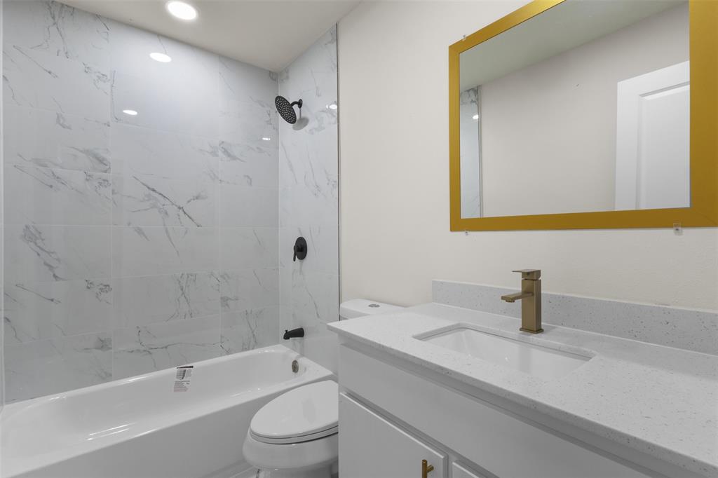 907 Pinson Road Forney, TX 75126 - Photo 19 of 35 Bathroom featuring a white vanity with an integrated rectangular sink, speckled countertop, and brushed gold faucet