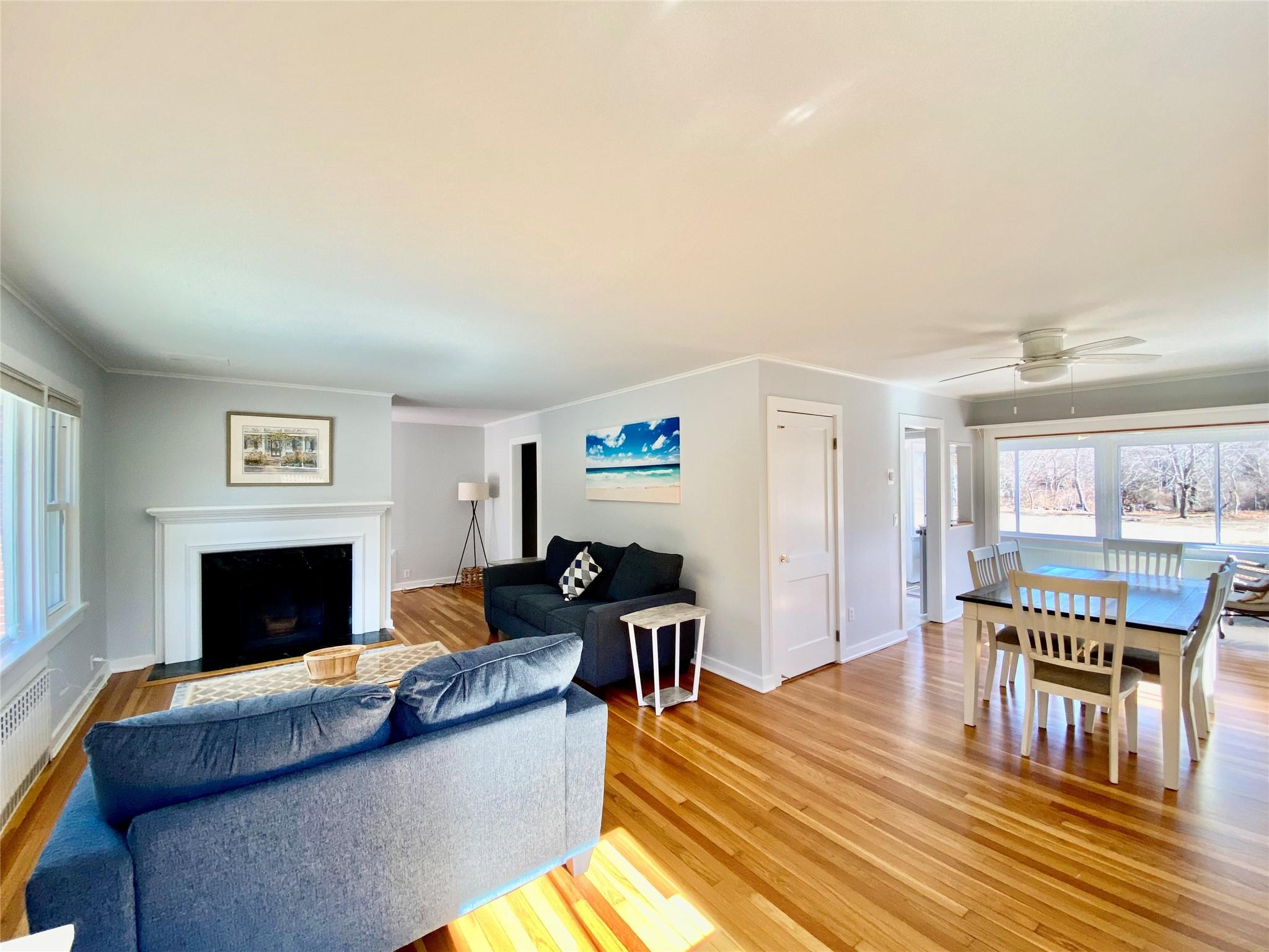 3825 South Harbor Road Southold, NY 11971 - Photo 3 of 15 Living room with baseboards, ceiling fan, light wood-style flooring, ornamental molding, and a fireplace with flush hearth