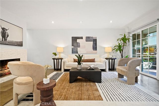 a living room with furniture a rug a lamp and a large window
