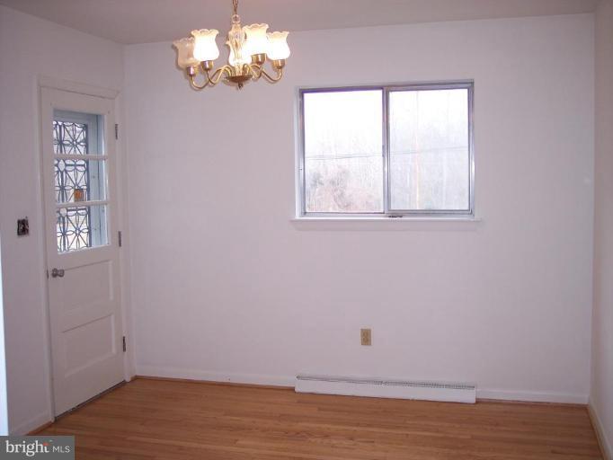 115 Ashton Road Ashton, MD 20861 - Photo 22 of 25 an empty room with wooden floor chandelier and window