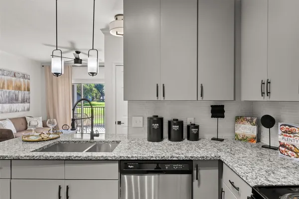 a kitchen with granite countertop a sink a counter space and cabinets