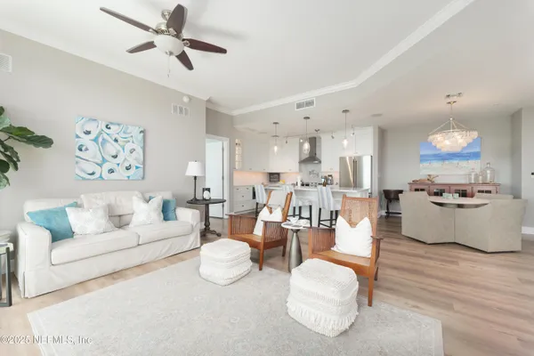 a living room with furniture kitchen view and a chandelier