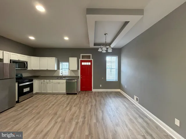 a large kitchen with stainless steel appliances a large counter top a stove and a refrigerator