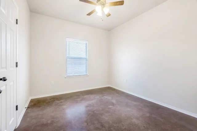 an empty room with a window and a ceiling fan