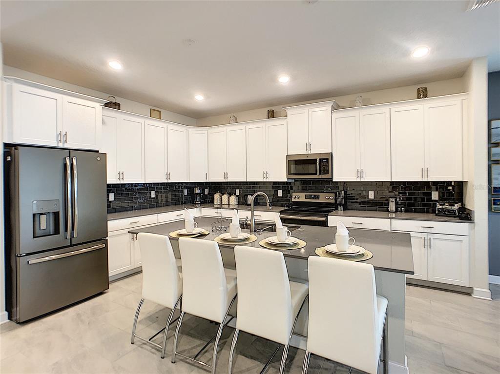 2736 Bookmark Drive Kissimmee, FL 34746 - Photo 4 of 35 a kitchen with stainless steel appliances granite countertop a refrigerator a stove top oven a sink and dishwasher