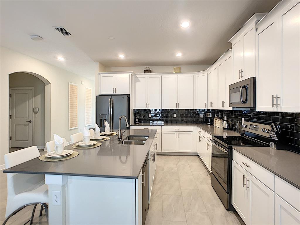 2736 Bookmark Drive Kissimmee, FL 34746 - Photo 5 of 35 a kitchen with stainless steel appliances kitchen island granite countertop a sink and cabinets