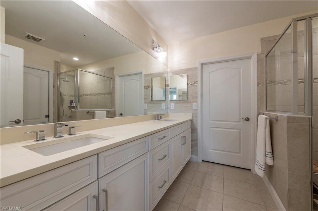 6954 Avalon Circle, Unit 702 Naples, FL 34112 - Photo 14 of 40 a bathroom with a double vanity sink and mirror