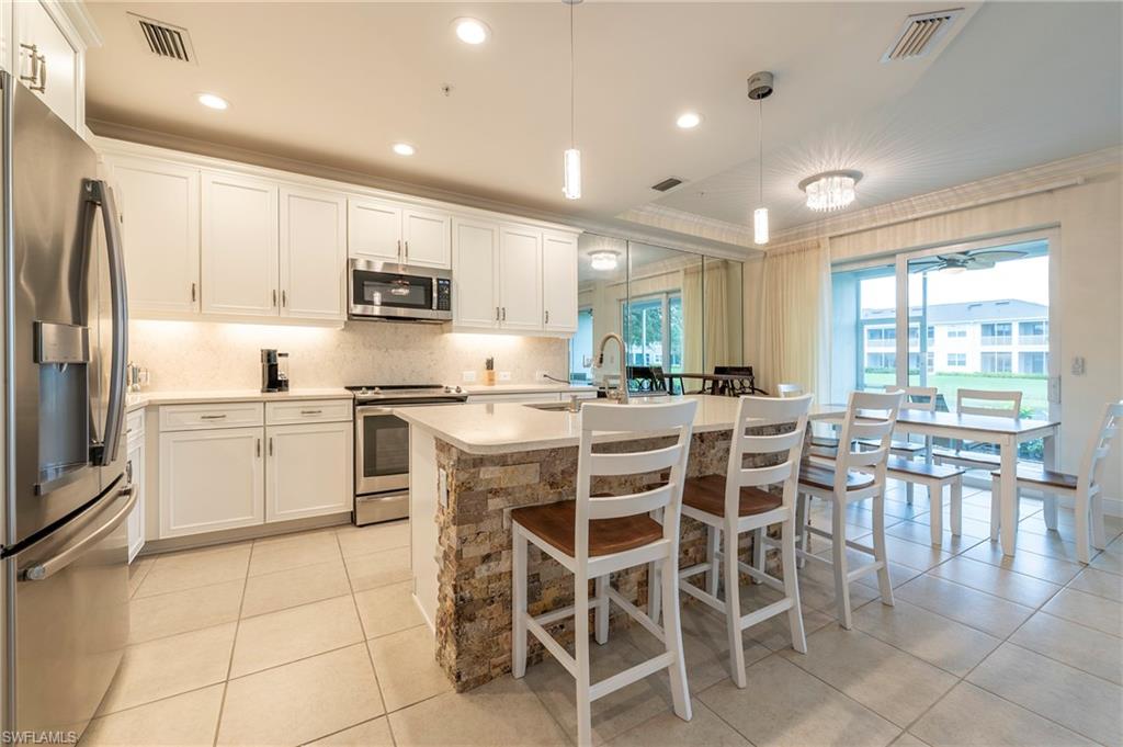 6954 Avalon Circle, Unit 702 Naples, FL 34112 - Photo 15 of 40 a kitchen with a dining table cabinets and appliances