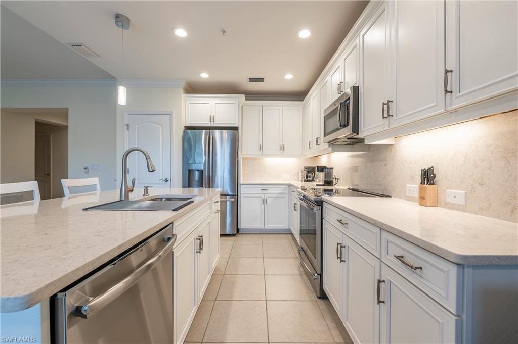6954 Avalon Circle, Unit 702 Naples, FL 34112 - Photo 20 of 40 a large kitchen with stainless steel appliances granite countertop a sink and cabinets