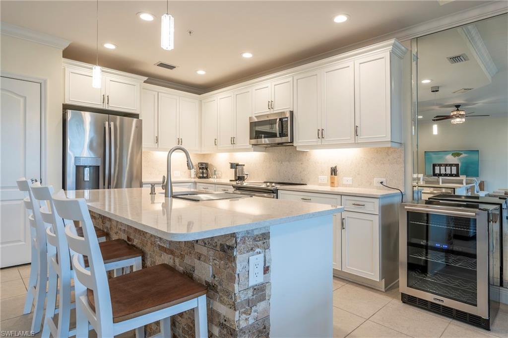 6954 Avalon Circle, Unit 702 Naples, FL 34112 - Photo 21 of 40 a kitchen with kitchen island granite countertop a sink and stainless steel appliances