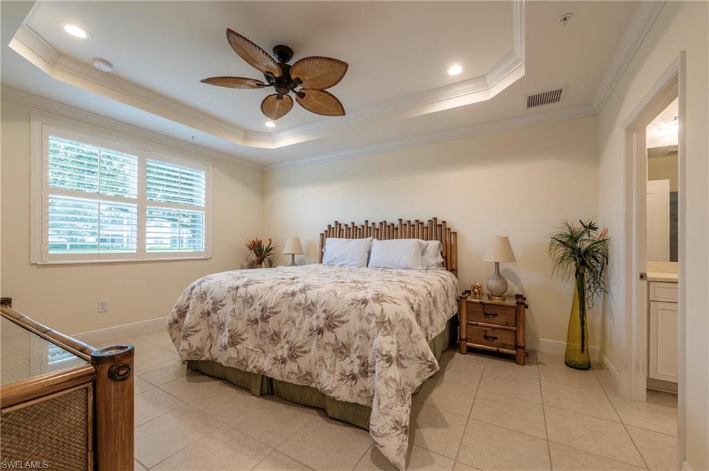 6954 Avalon Circle, Unit 702 Naples, FL 34112 - Photo 7 of 40 a bedroom with a bed and a chandelier