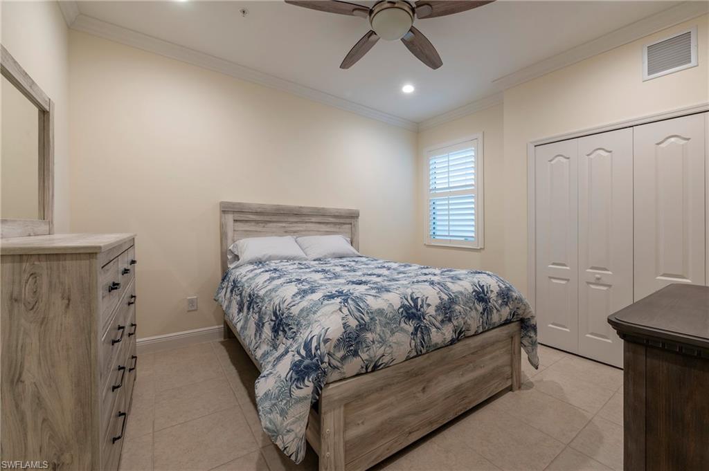 6954 Avalon Circle, Unit 702 Naples, FL 34112 - Photo 10 of 40 a bed sitting in a bedroom next to a window and a chandelier