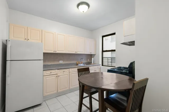 a kitchen with stainless steel appliances a white table chairs and a refrigerator