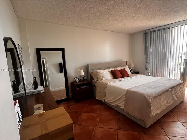 a bedroom with a bed a couch and a flat tv screen on the dresser