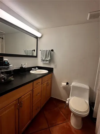 a bathroom with a granite countertop toilet sink and mirror