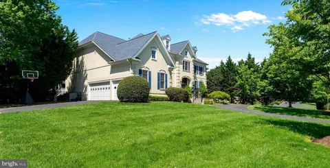 a view of a house with a big yard and potted plants and large trees