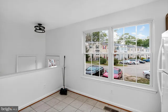 a view of an empty room with wooden floor kitchen view and a window
