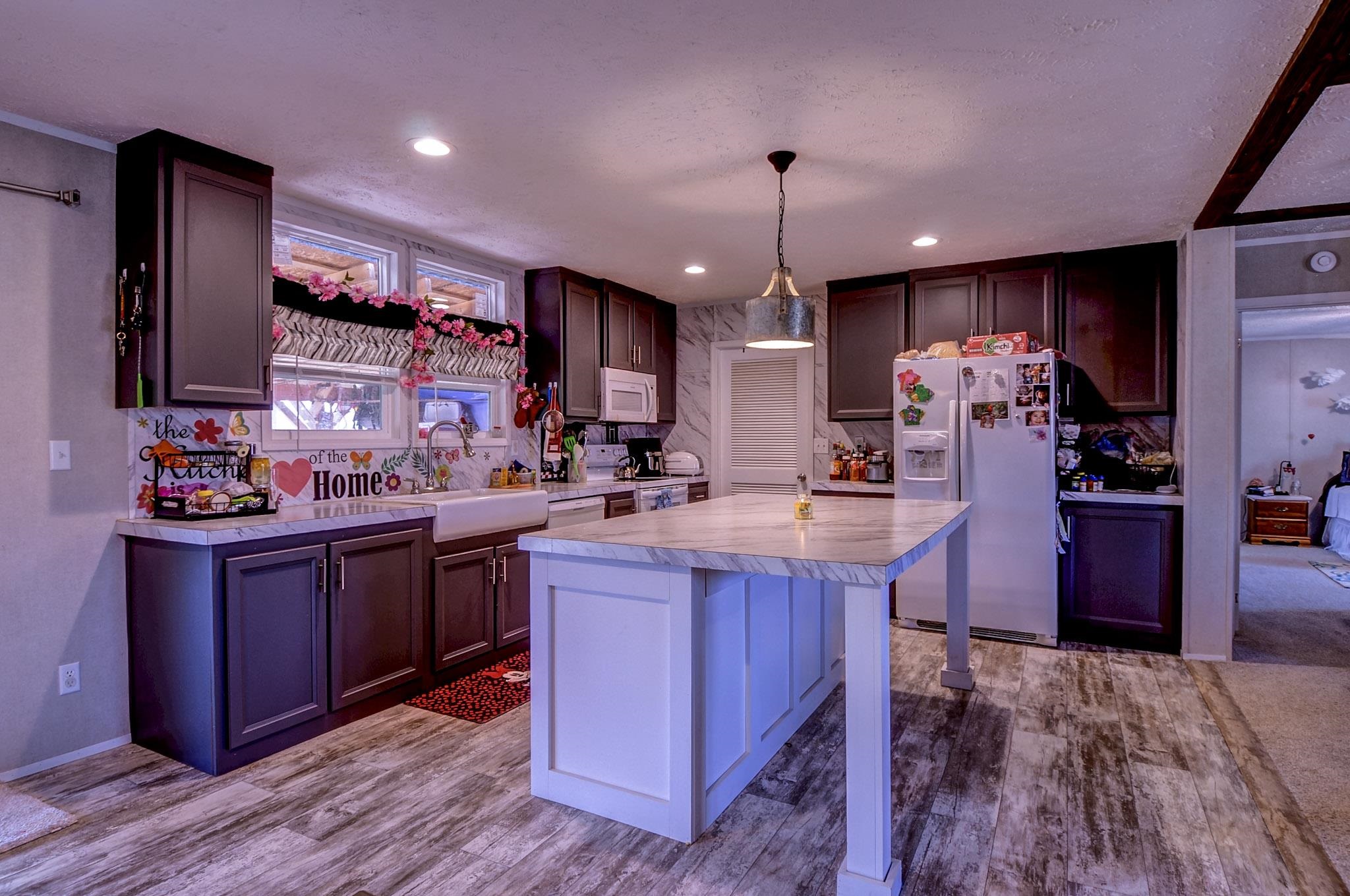 2450 South Neely Road Middleton, TN 38052 - Photo 11 of 38 Two tone kitchen featuring light countertops, a breakfast bar area, white appliances, pendant lighting, and a kitchen island