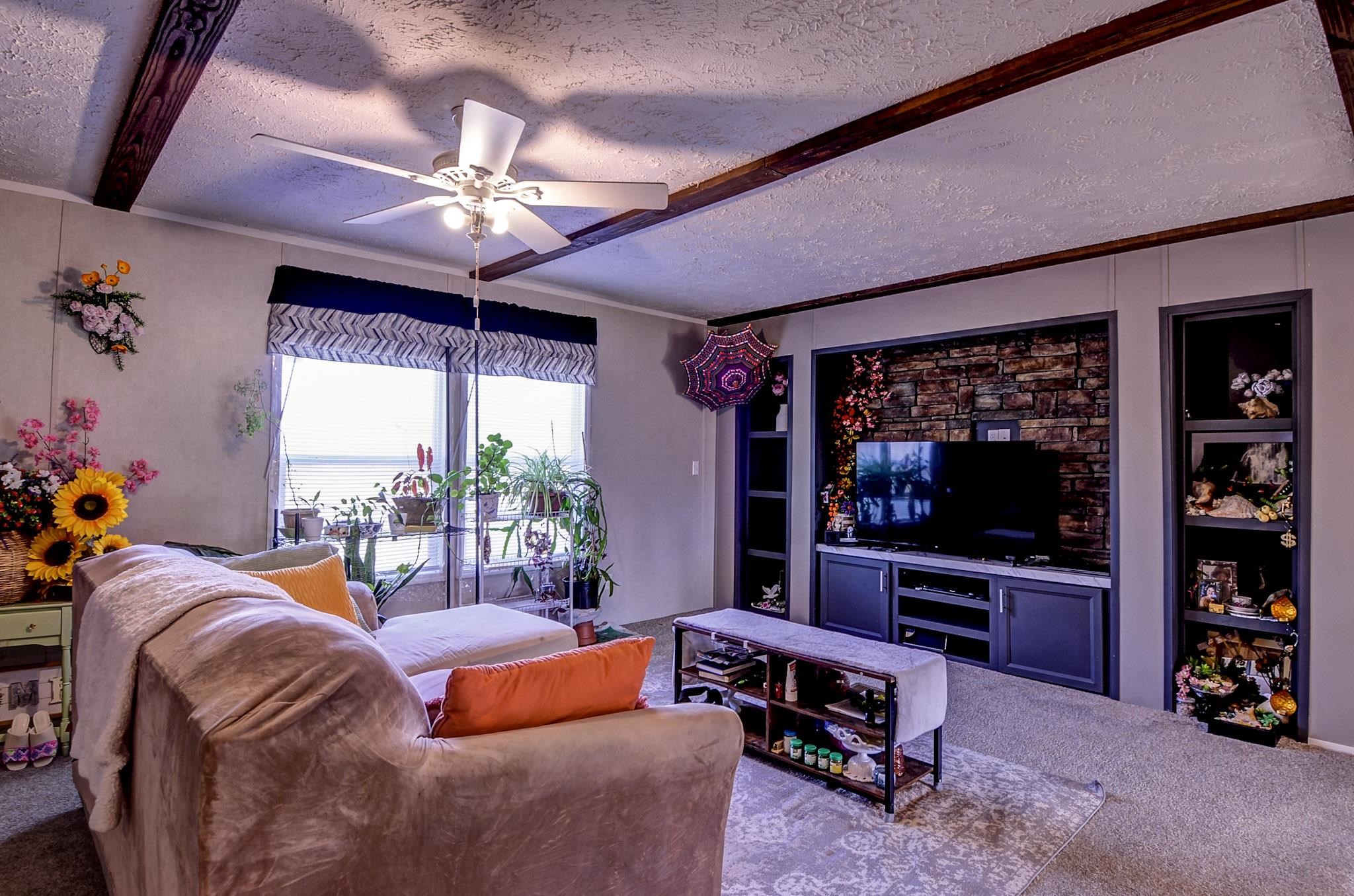 2450 South Neely Road Middleton, TN 38052 - Photo 14 of 38 Living room featuring a ceiling fan, a textured ceiling, built in shelves, carpet, and crown molding