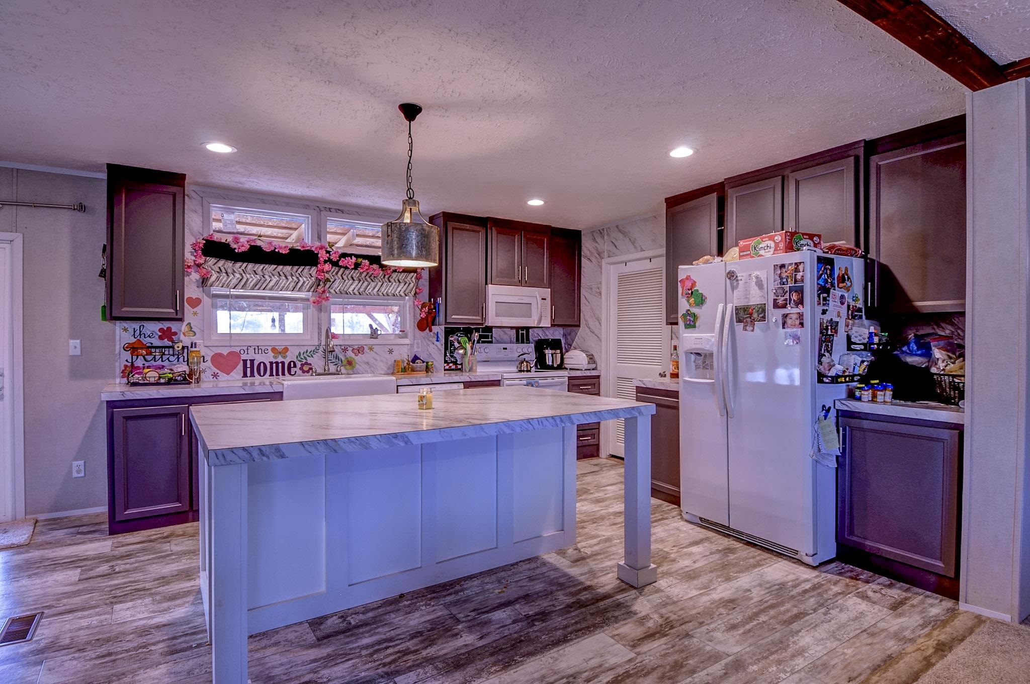 2450 South Neely Road Middleton, TN 38052 - Photo 8 of 38 Kitchen with white appliances, pendant lighting, light wood-style floors, a center island, and a textured ceiling