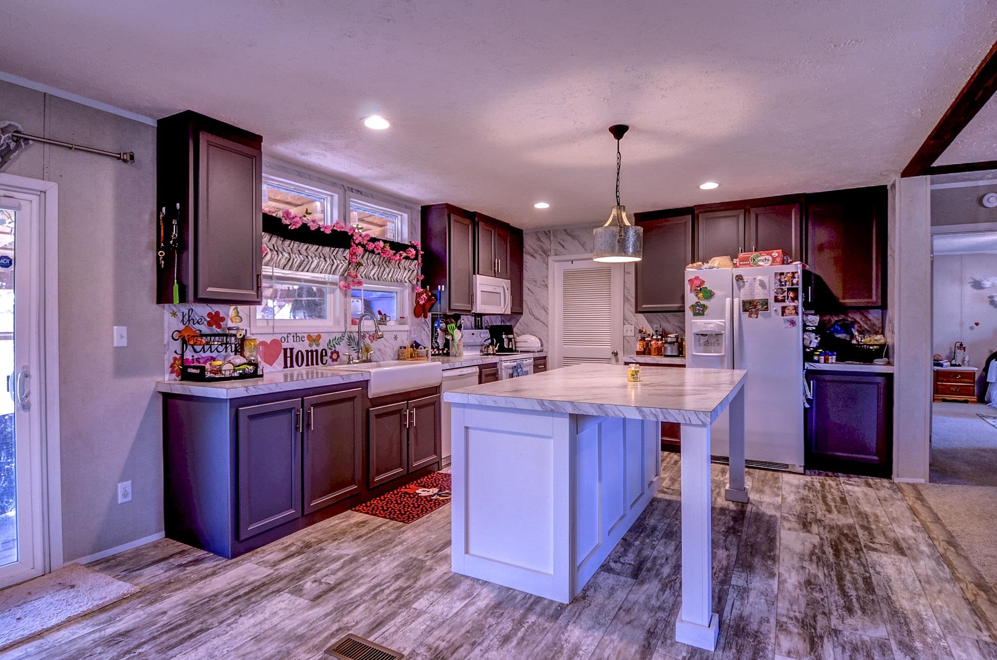 2450 South Neely Road Middleton, TN 38052 - Photo 9 of 38 Dual tone kitchen with light countertops, white appliances, a breakfast bar, dark wood-type flooring, and hanging light fixtures