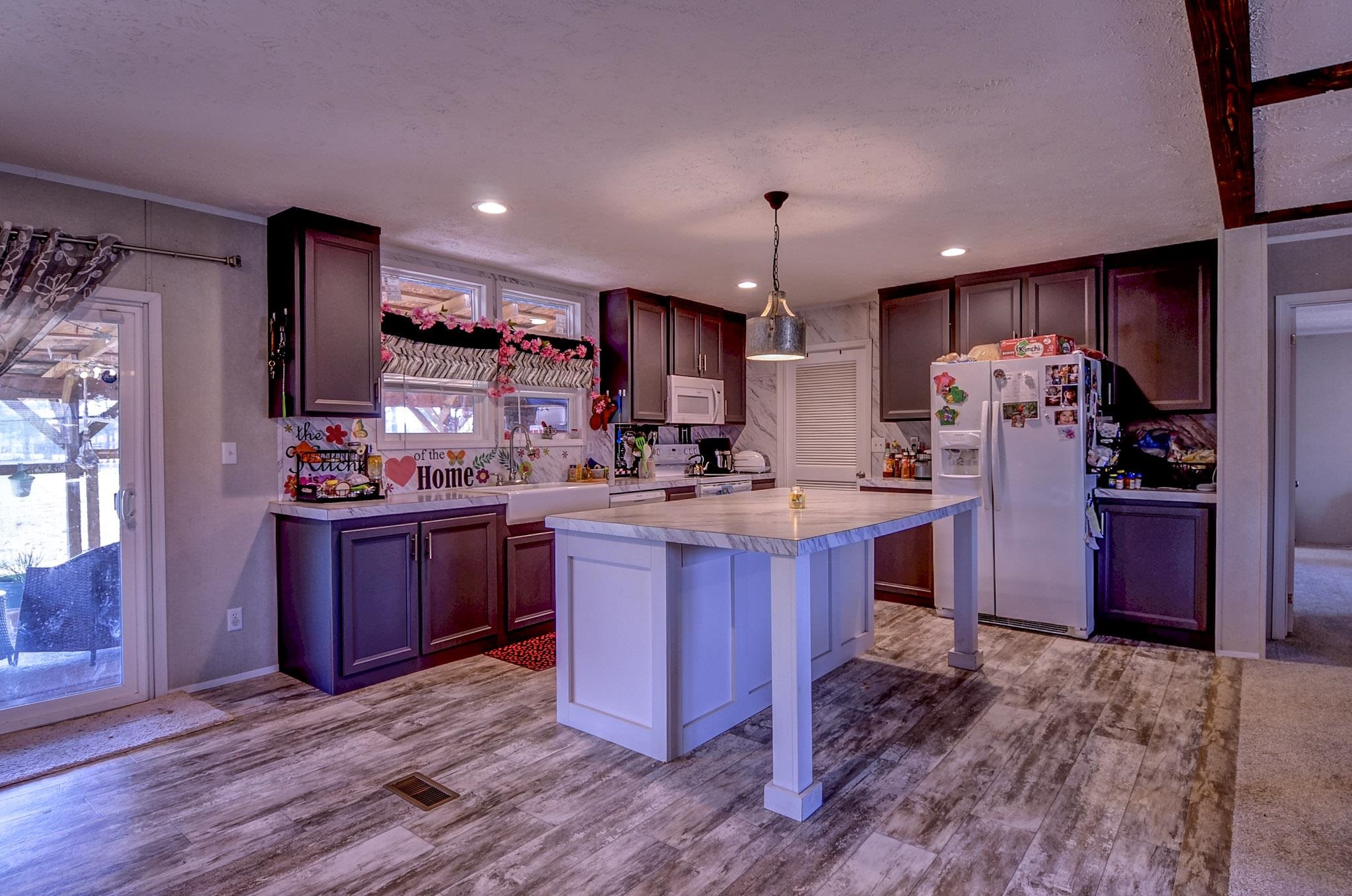 2450 South Neely Road Middleton, TN 38052 - Photo 10 of 38 Kitchen featuring light countertops, white appliances, a breakfast bar, decorative light fixtures, and dark wood-type flooring