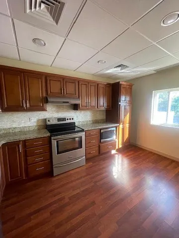 a kitchen with granite countertop wooden floors a stove and a microwave