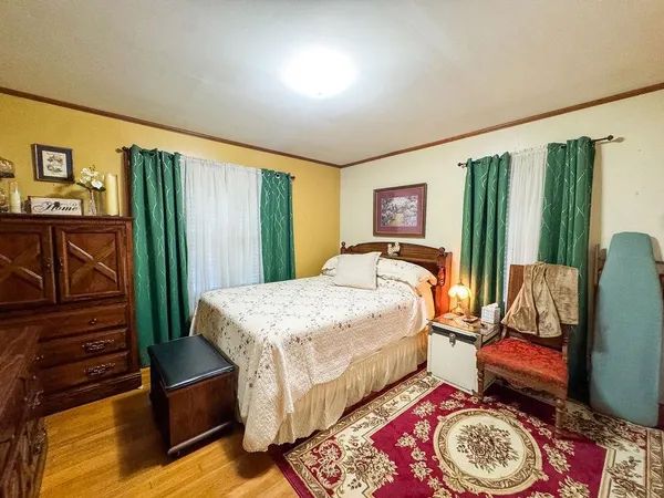 a bedroom with a bed and a dresser with wooden floor