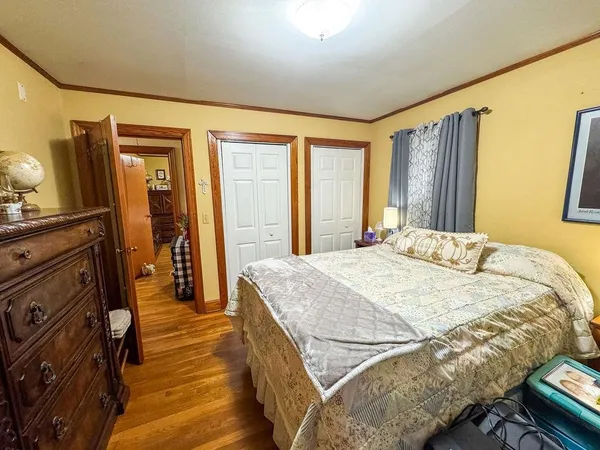 a spacious bedroom with a bed and wooden floor