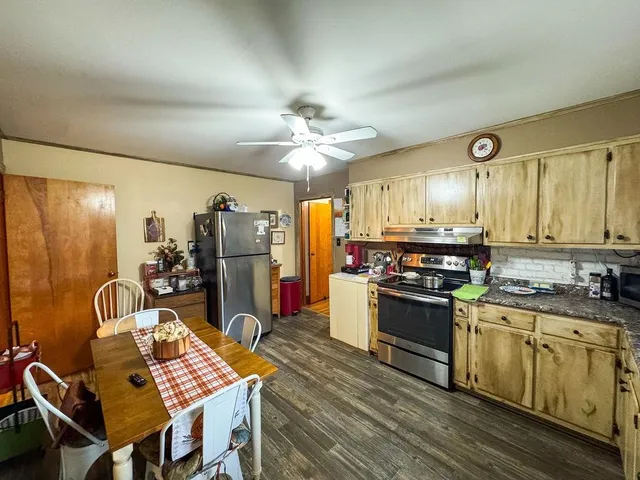 a kitchen with stainless steel appliances kitchen island granite countertop a stove a sink dishwasher and a refrigerator with wooden floor