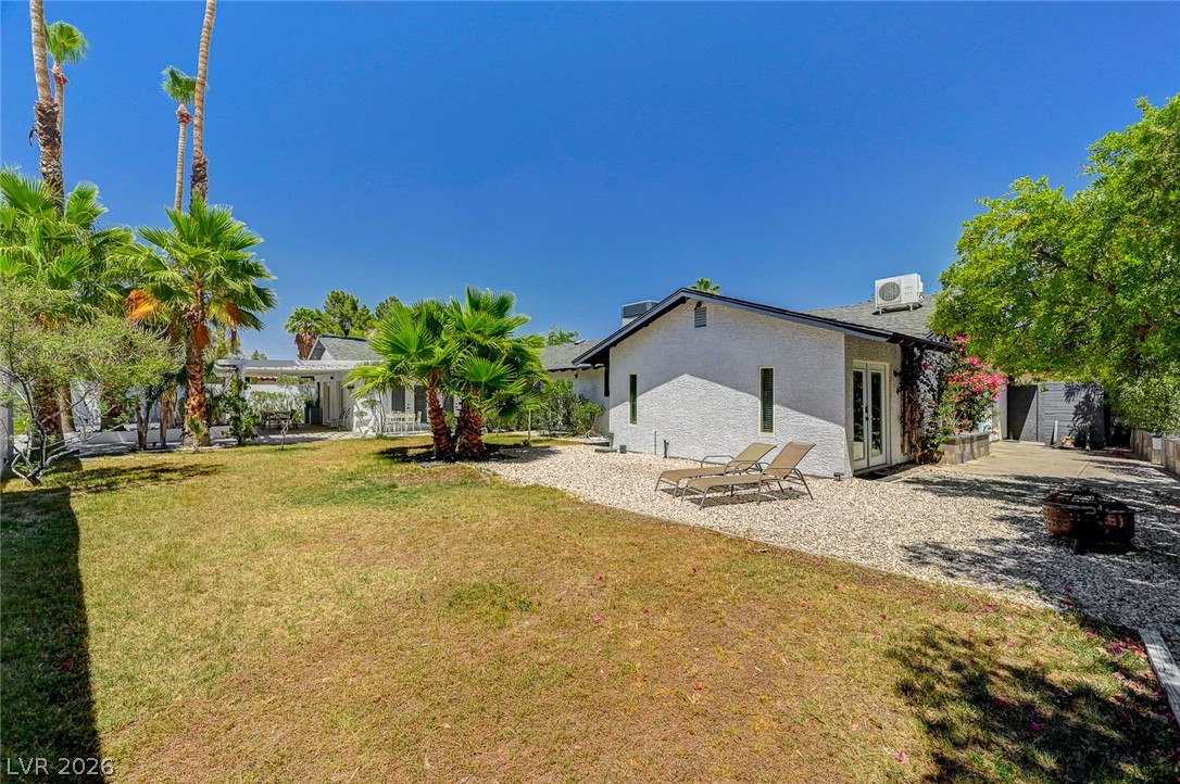 4153 Woodcrest Road Las Vegas, NV 89121 - Photo 47 of 58 A spacious yard with mature palms and desert landscaping surrounds this white stucco home, offering a tranquil retreat.