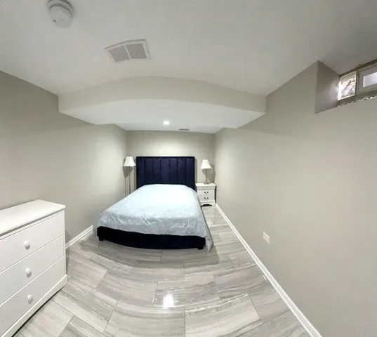 a bedroom with a bed and a lamp on dresser