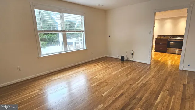 a view of an empty room with wooden floor and a window