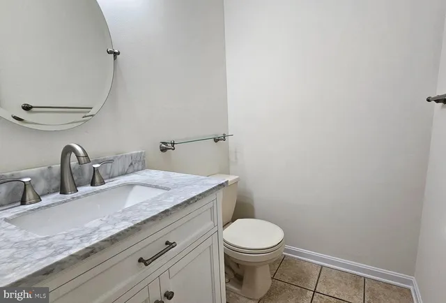 a bathroom with a granite countertop sink a toilet and mirror