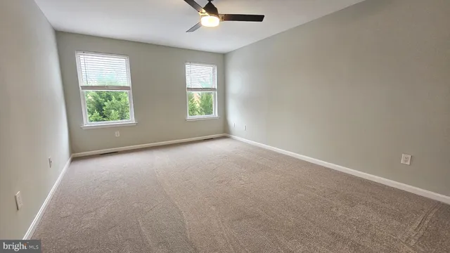 an empty room with windows and ceiling fan view