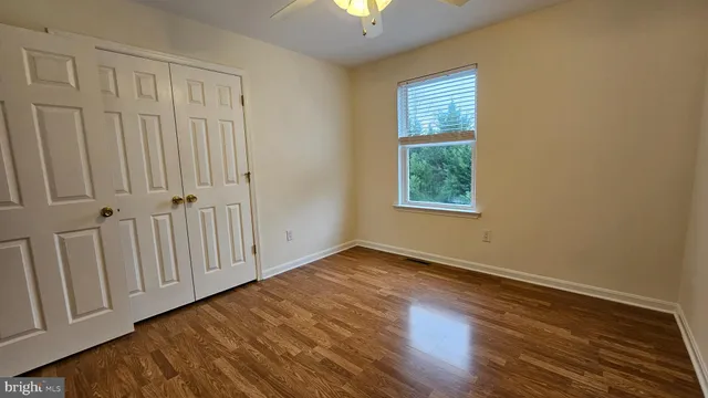 an empty room with wooden floor closet and windows