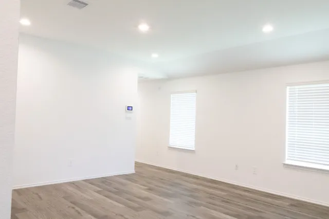 an empty room with wooden floor and windows