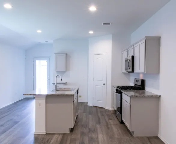 a kitchen with a sink cabinets and wooden floor