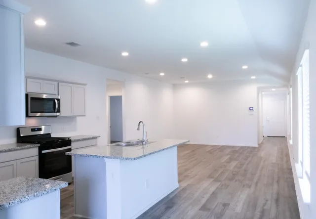 a kitchen with kitchen island granite countertop a sink wooden floor and black appliances