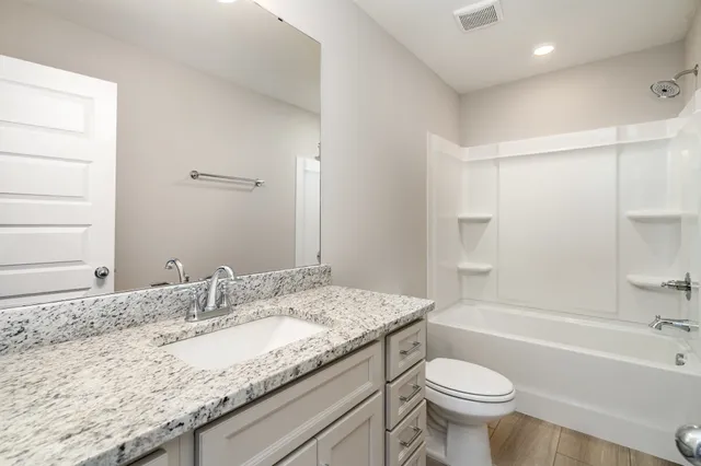 a bathroom with a granite countertop sink toilet mirror and bathtub