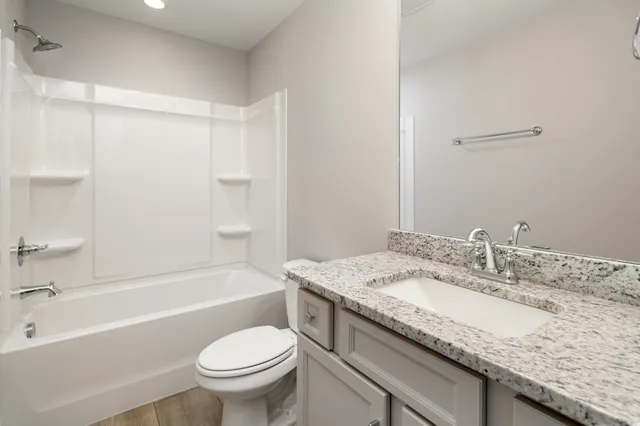 a bathroom with a granite countertop sink a toilet and bathtub