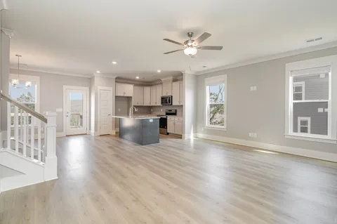 a view of an empty room with wooden floor and a kitchen
