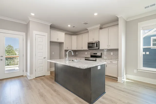 a kitchen with stainless steel appliances granite countertop a stove top oven a refrigerator a sink and a microwave with wooden floor