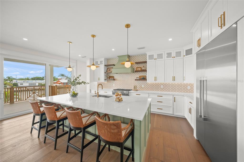 525 68th Street Holmes Beach, FL 34217 - Photo 9 of 52 a kitchen with stainless steel appliances kitchen island granite countertop a table chairs stove and white cabinets