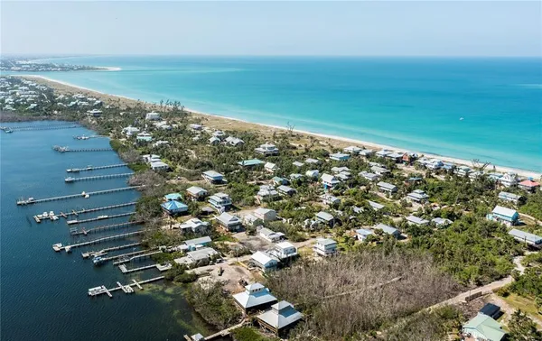 an aerial view of ocean and residential houses with outdoor space