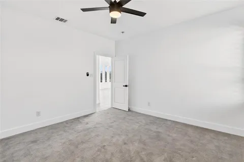 an empty room with a ceiling fan and carpet