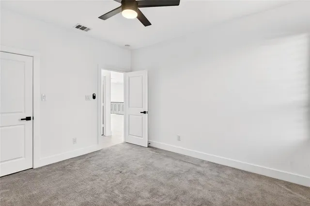 an empty room with a ceiling fan and carpet