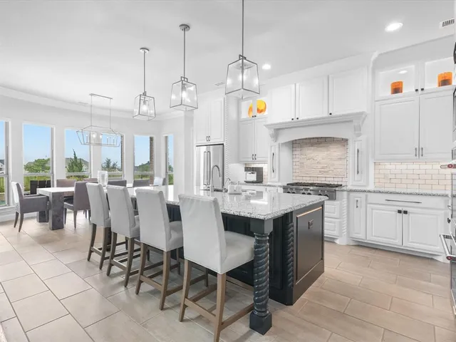 a large white kitchen with granite countertop a sink counter space stainless steel appliances and cabinets